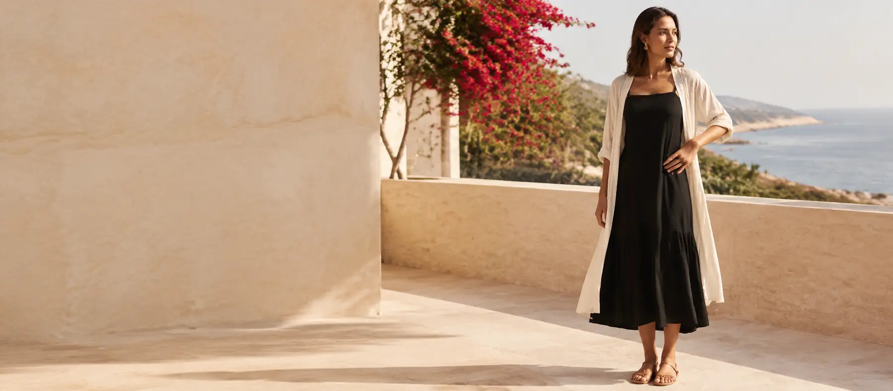 Mujer con vestido negro en una terraza luminosa frente al mar